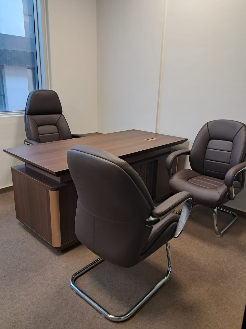 Bureau de direction bois foncé avec trois fauteuils bruns.