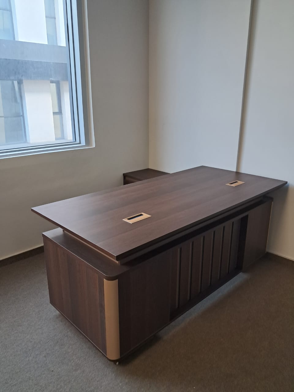 Bureau de direction bois foncé avec passages de câbles sur le plateau.