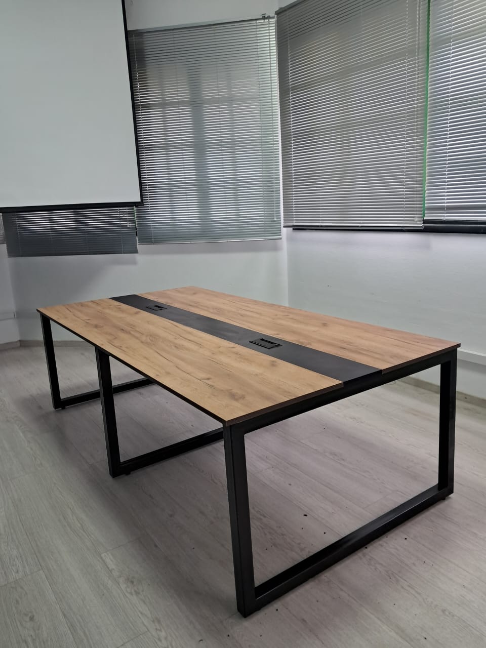 Table de réunion à plateau bois et piètement métallique noir.